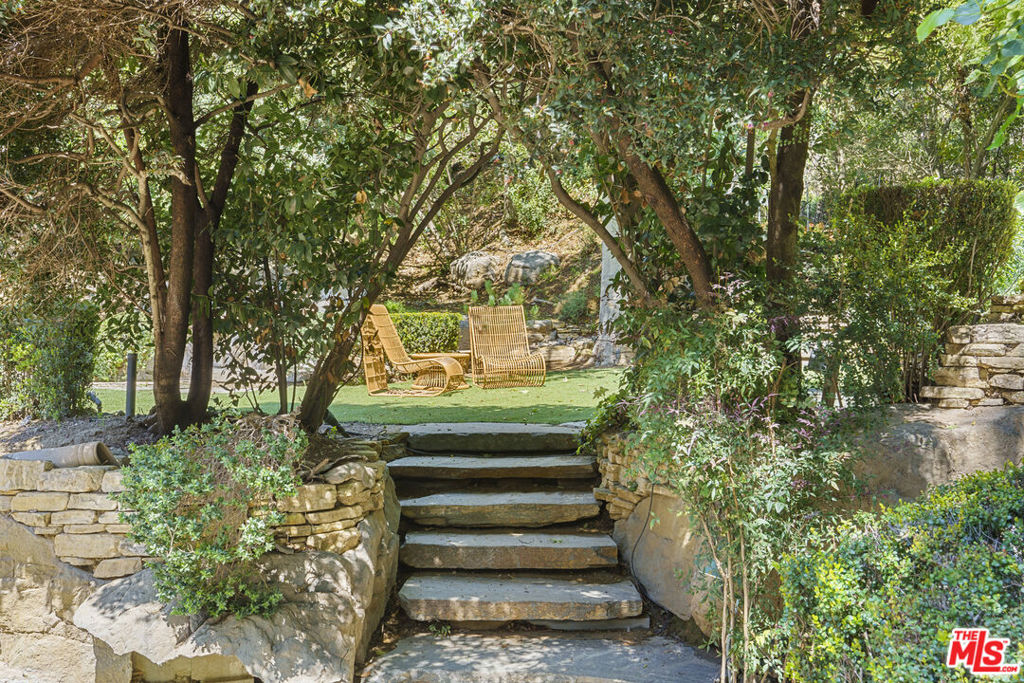 Cher loved it and put her tasteful mark on it. Discover an exquisite blend of privacy, refinement, and rustic English charm in this meticulously remodeled Artists Retreat nestled within the prestigious enclave of Beverly Hills. Formerly a Celebrity Estate, this gated haven is discreetly situated at the end of a secluded, private road, offering unparalleled seclusion and tranquility. Step inside to be enchanted by the timeless charm and character felt from every corner of this charming property. Adorned with storybook windows and rustic wood beam ceilings, the residence welcomes you with warmth, evoking the ambiance of a rustic English charmer. Indulge in the built-in breakfast nook, framed by bay windows, or gather around the cozy fireplace that graces the living space. French doors seamlessly connect the dining area and living room to the secluded front space, where a captivating gargoyle fountain sets the scene for outdoor relaxation and dining amidst lush surroundings.