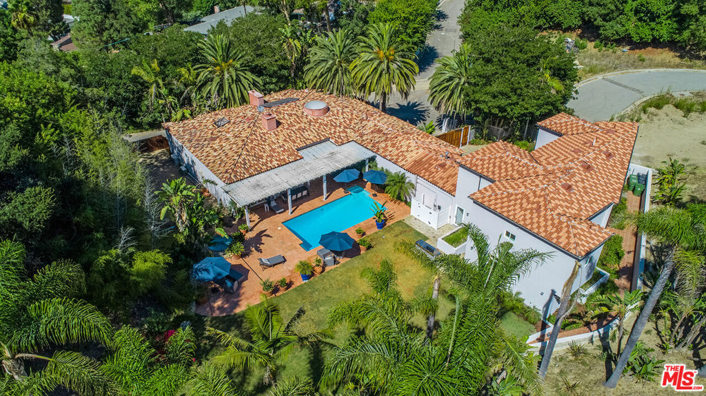 This enchanting Mediterranean estate is nestled within a serene, private neighborhood and surrounded by lush greenery and stunning natural scenery. Set on a nearly one-acre corner lot, the property boasts expansive lawns framed by majestic palm trees, offering a private, resort-like ambiance. The estate features 8 bedrooms and 11 bathrooms, including a formal living room, den, and dining room. Designed with both large and intimate gatherings in mind, it is perfect for home offices or extended families. The open floor plan is enhanced by high ceilings and each of the 8 bedrooms includes an en suite bathroom. The northern wing, newly built in 2019, includes 3 bedrooms upstairs, a living room, kitchenette, and a private entrance, making it ideal for use as a guest house, office, studio, or staff quarters. A lower-level addition off the garage serves as a bedroom or security office with its own entrance. The southern wing features 4 ground-floor bedrooms, with the expansive primary suite offering his and hers bathrooms and two walk-in closets. The gourmet kitchen, which opens to the family room, provides breathtaking views of the grounds through walls of glass. The backyard is a private oasis with a covered patio perfect for outdoor dining, a sparkling pool, a spa, a volleyball court, and ample space for a tennis court or pickleball. Additional amenities include two laundry rooms one adjacent to the kitchen and another in the garage. A fabulous family estate as well as ideal for major cash flow for vacation rentals.