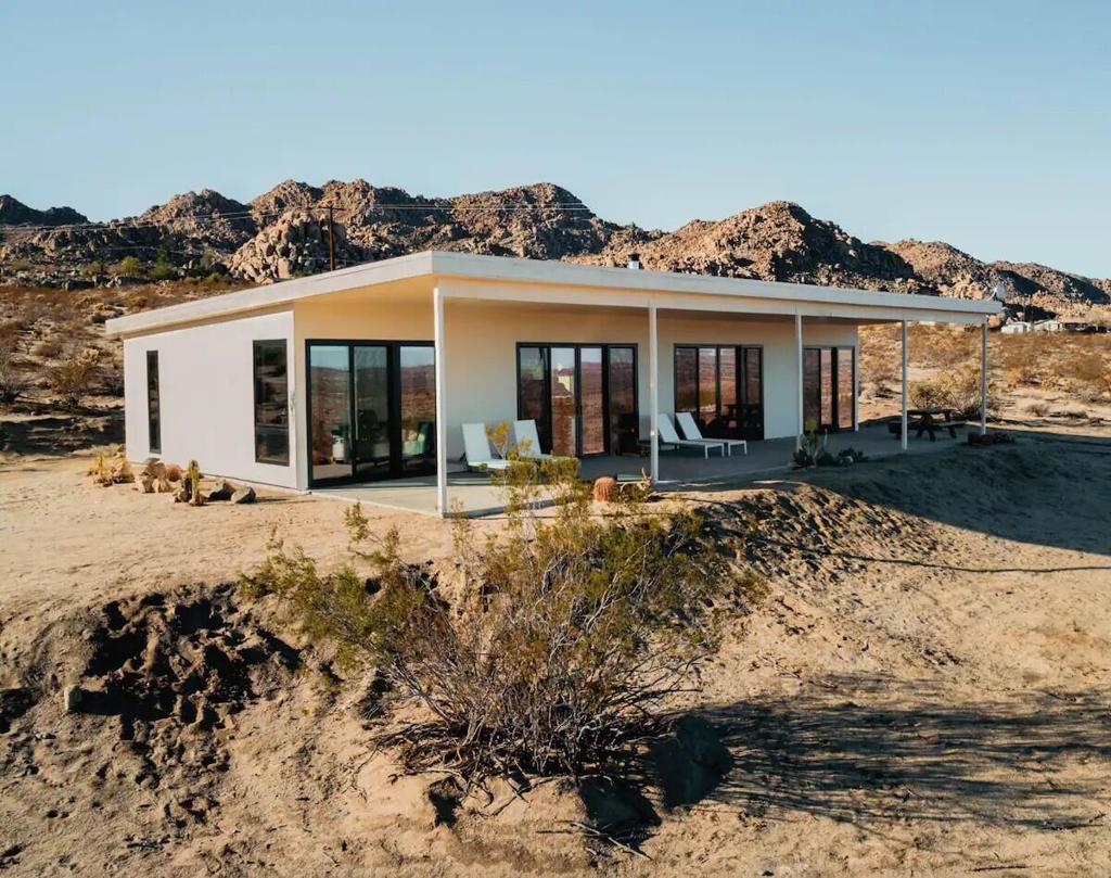 New construction, modern architectural home professionally designed by Duane Smith an award winning designer. This permitted STR can be offered furnished turnkey. Featuring a stunning location at the top of Joshua Tree with nearly 4 acres of land & beautiful views in Panorama Heights. Step inside to find a sprawling layout bathed in natural light, highlighting the luxurious mid-century details throughout. 1,408 sf with high ceilings & large windows with skyline vistas. The spectacular grandeur of boulder studded hills to the south & the vast valleys & hills below are truly inspiring. Polished concrete floors & recessed lighting. Ac-mini splits. Solar system paid. Spacious living room with a wood stove. The sleek kitchen, with new stainless appliances & a stunning quartz island. Perfect for entertaining guests. 2 beds & 2 baths. Bathroom with floating vanity, custom concrete & glass shower.  Expansive covered patio. Spa & lounge recliners. Horse property. Starry nights with shimmering city lights. High end new homes & designer remodels can be seen all around this neighborhood. Just a few streets south is the border to the JT National Park with enchanting boulder laden canyons & hiking trails. Less than 3 miles to the JT strip with organic cafes, restaurants, the saloon, & the farmers market. 13 miles to Joshua Tree National Monument where about 3 million tourists visit annual. 43 miles to Palm Springs. 131 miles to LA. Don't wait on this one call now!