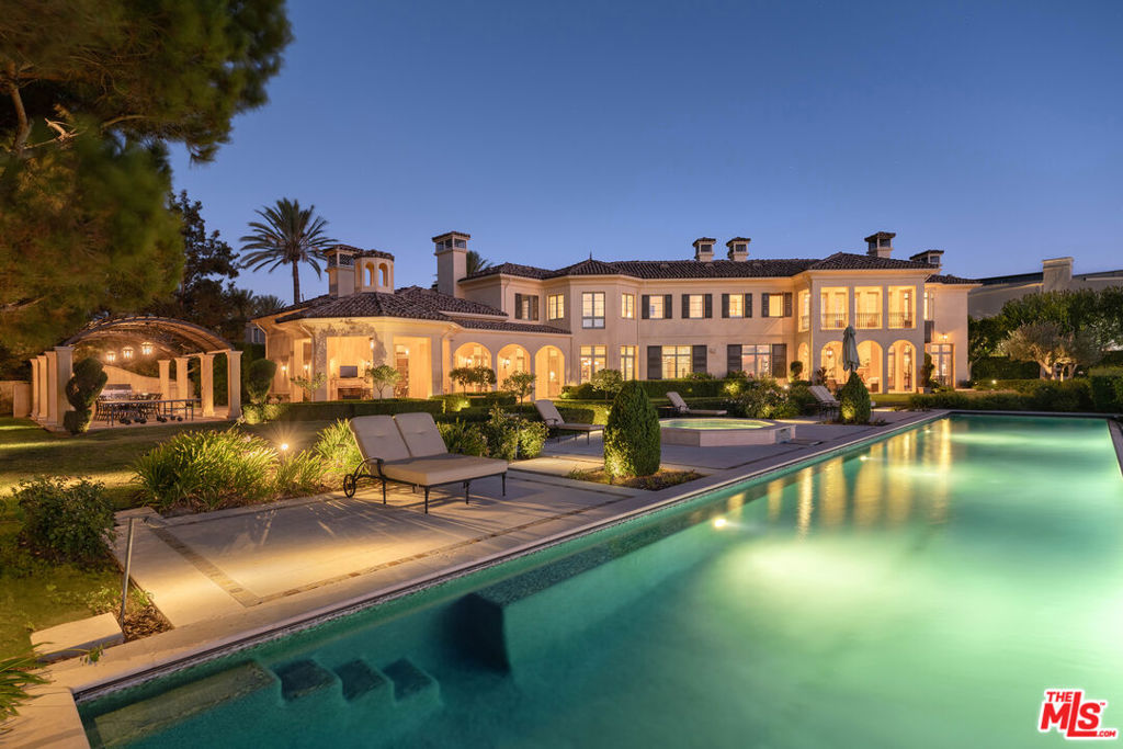 Welcome to an exquisite residence within the prestigious gated community of Mulholland Estates a home where elegance and refinement are not merely features, but a way of life. This Tuscan-inspired villa, designed by the celebrated Dean Larkin, AIA, is an ode to timeless sophistication, set upon a double lot, the sixth largest and one of the most coveted in the community. The estate offers unparalleled privacy and breathtaking panoramic views of city lights and the San Gabriel Mountains, surrounded by lush mature landscaping, topiary gardens, and tranquil water features, creating a peaceful and secluded sanctuary. As you enter through the large cobblestone motor court, the home's palatial interiors begin with a grand entry foyer, crowned by a breathtaking Swarovski crystal chandelier, that sets the tone for the scale and volume that define this residence. Tall archways, glowing sconces, and limestone floors guide you through the formal living spaces, where stone fireplaces and French doors open directly to the expansive outdoor grounds. The brand new chef's kitchen is a masterpiece of form and function, equipped with porcelain slab countertops, top-tier appliances, including three Sub-Zeros, and a dining area that flows effortlessly into the family room, perfect for intimate gatherings. An elegant formal dining room and a wood-paneled library embody the essence of classic luxury, while the game/theater room with a wet bar and soaring 20-foot beamed ceilings provides a space for relaxation and entertainment. Ascending to the upper level, the primary suite offers a haven of unparalleled luxury. A stone fireplace sitting lounge overlooks the endless valley vistas, while the spacious balcony and immaculate onyx bathroom complete with heated floors, dual vanities, large shower, and a soaking tub framed by bay windows invite you to unwind in supreme comfort. The outdoor spaces are nothing short of a private paradise. An infinity pool and jacuzzi, set against the dazzling backdrop of Los Angeles, are accompanied by an outdoor kitchen, al fresco dining area under an iron pergola, and multiple seating lounges, all designed for the art of entertaining. Additional amenities include an elevator, gym, two laundry rooms, and a temperature-controlled wine room. This estate is not just a home, but a retreat, offering the perfect balance of luxury, privacy, and convenience in one of Los Angeles' most sought-after communities.