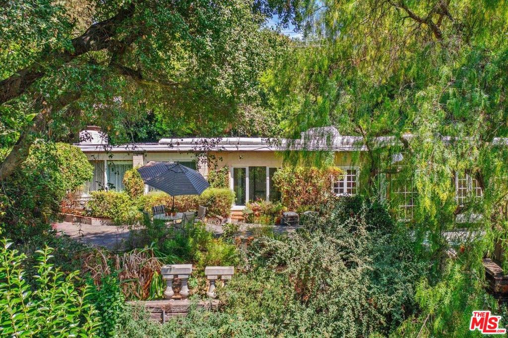 Paradise Found! Be at one with nature in this magical, gated estate sited on a breath-taking 32K square foot lot in a rustic, pastoral setting where the views enchant, soft breezes waft, and the sounds of the canyon abound, and just minutes from the Westside or the SF Valley. This rustic, woodsy retreat is perfect for those who long for a home that conjures inspiration. These are just some of the reasons this estate is a great fit for artists, musicians, or performers, but this beautiful view lot is also ideal for builders & flippers. This is what drew the seller to her haven some 50 years ago. Enter through French doors into the large wood and glass foyer/sunroom. With its raised ceiling, clerestory windows and distressed, wood floors it flows seamlessly into the living room of rangy scale which leads conveniently to the updated country kitchen featuring stone counters, updated appliances, and impressive workspace. This open plan is ideal for all sorts of festive gatherings and quiet moments. The primary and secondary bedrooms are on opposite wings of the public rooms offering privacy for all bedrooms. It also offers the option to create a home office, music studio or guest bedroom far from the primary sleeping quarters. The primary suite features a sitting room/den, fireplace, a full bathroom with soaking tub and a copiously spacious walk-in closet. The grounds are stellar and include a huge wrap around patio featuring a reflection/plunge pool with fountain, a hot tub, a free-standing storage room and a well-appointed workshop (with studio-conversion possibilities). Beyond the broad level building pad lies a lush, terraced slope, (affectionately referred to as "the jungle" by its owner) which gracefully descends down the hillside into the canyon and features numerous fruit and specimen trees (see description in "Reports"). And for the horticulturist, there's a large, fenced-in garden (which may possibly be modified into a greenhouse) all easily accessed by several descending staircases. This exquisite estate holds a very special place in the seller's heart, and she can't wait to discover who the next lucky owner will be.